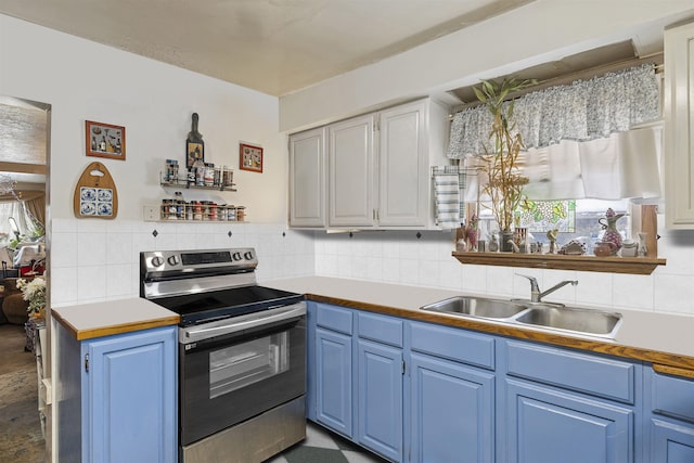 kitchen with tasteful backsplash, electric stove, blue cabinets, light countertops, and a sink