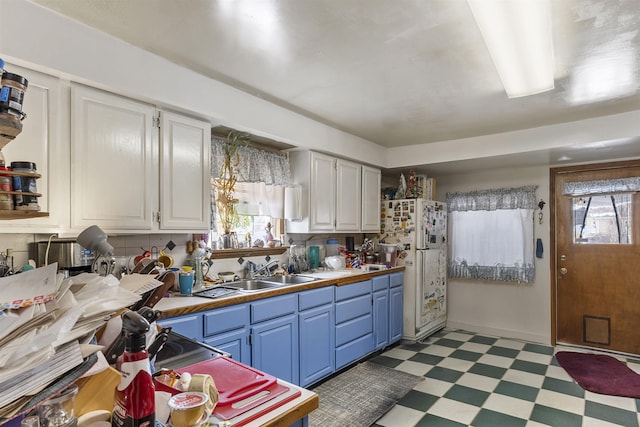 kitchen featuring blue cabinetry, dark floors, white cabinetry, and a sink