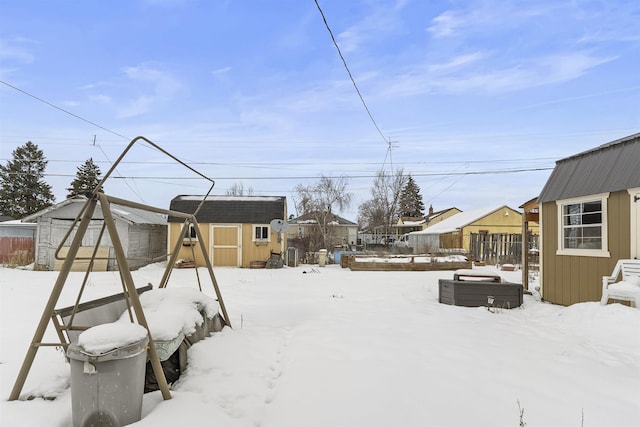 yard layered in snow featuring an outbuilding, a shed, and fence