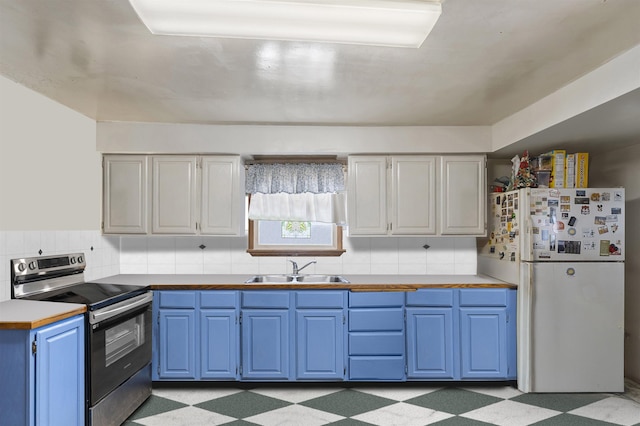 kitchen with a sink, electric stove, blue cabinetry, freestanding refrigerator, and light floors