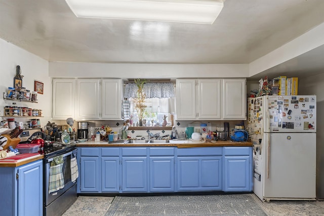 kitchen with electric range, freestanding refrigerator, blue cabinetry, white cabinetry, and a sink