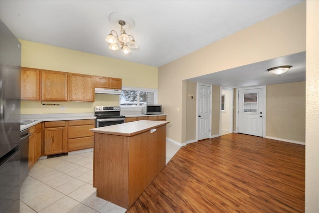 kitchen featuring a chandelier, under cabinet range hood, stainless steel appliances, light countertops, and decorative light fixtures