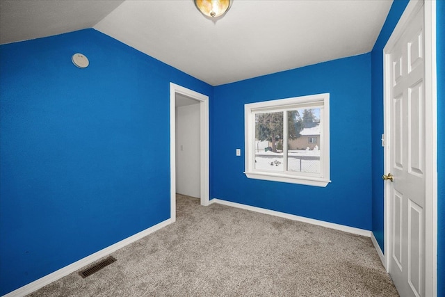 unfurnished bedroom featuring baseboards, visible vents, vaulted ceiling, and light colored carpet