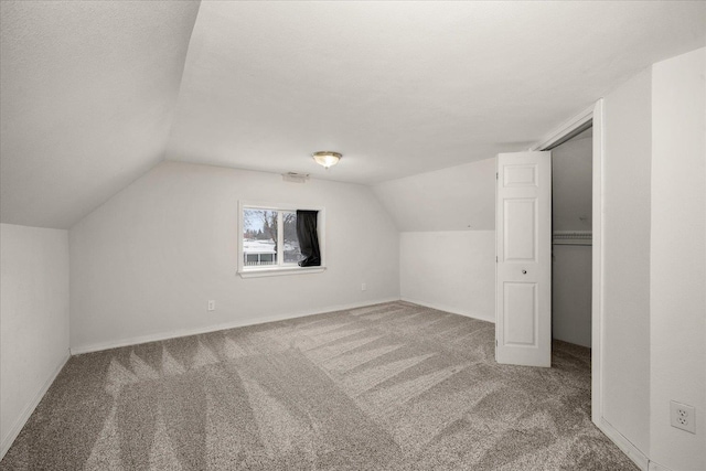 bonus room featuring vaulted ceiling, a textured ceiling, and carpet flooring