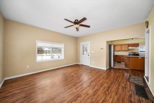 unfurnished living room with dark wood-style floors, ceiling fan, visible vents, and baseboards