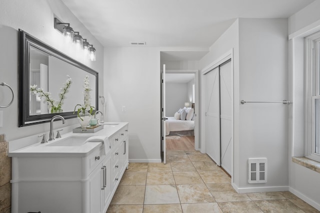 ensuite bathroom with ensuite bathroom, double vanity, a sink, and visible vents