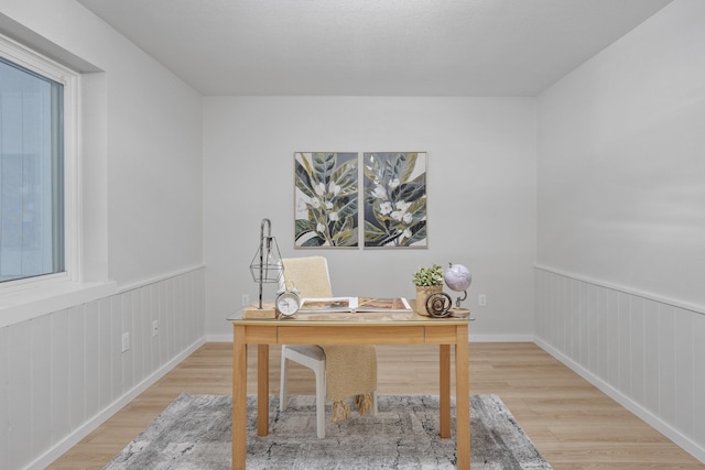 home office featuring a wainscoted wall and wood finished floors