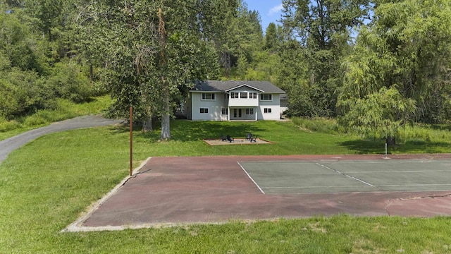 view of tennis court featuring basketball hoop and a lawn