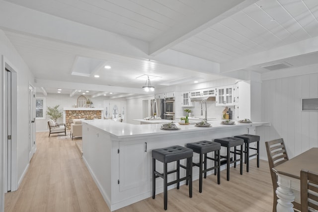 kitchen featuring white cabinets, glass insert cabinets, a peninsula, stainless steel appliances, and light countertops