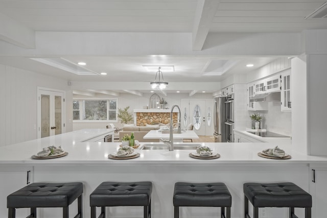 kitchen featuring white cabinets, glass insert cabinets, light countertops, and a breakfast bar area