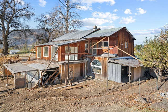 back of house with metal roof and an outdoor structure