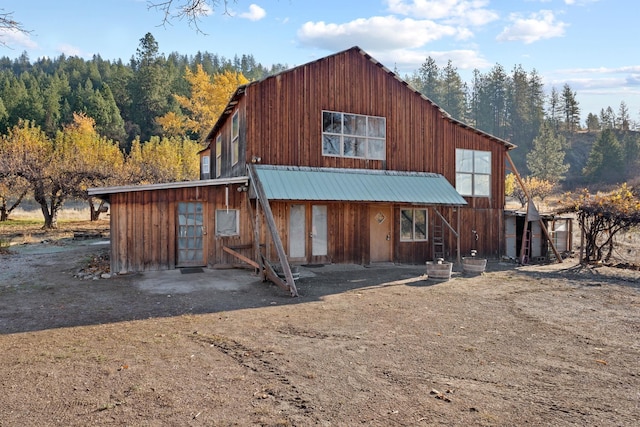 view of front of house with metal roof and a view of trees