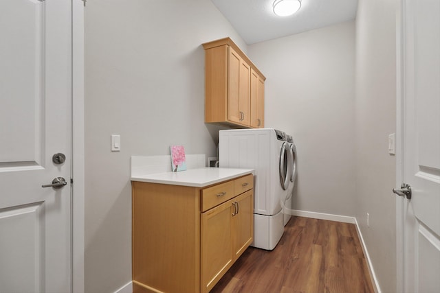 washroom featuring cabinet space, baseboards, dark wood-type flooring, and washer and dryer