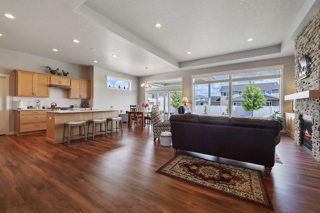 living area featuring a textured ceiling, dark wood-style flooring, a fireplace, and recessed lighting