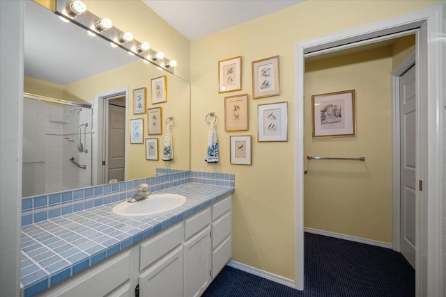 bathroom with baseboards, a shower, and vanity