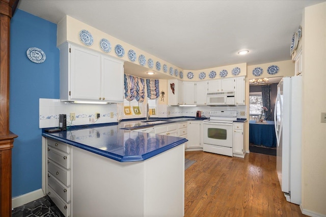 kitchen with white appliances, dark countertops, white cabinetry, and tasteful backsplash