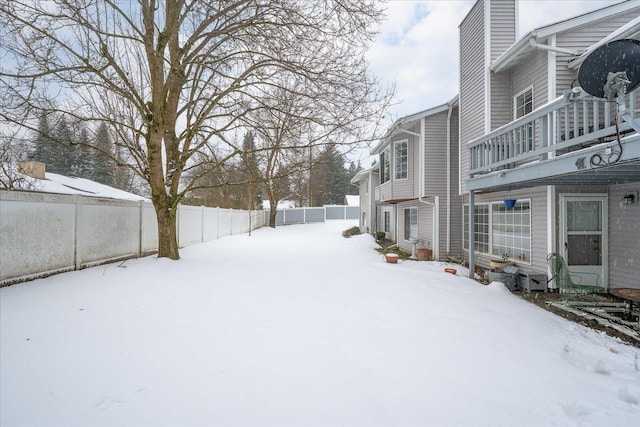 yard covered in snow with a fenced backyard