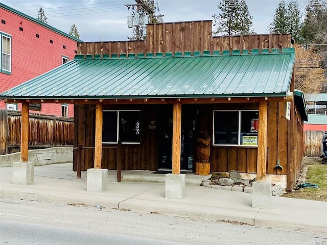 view of front of home with board and batten siding, metal roof, and fence