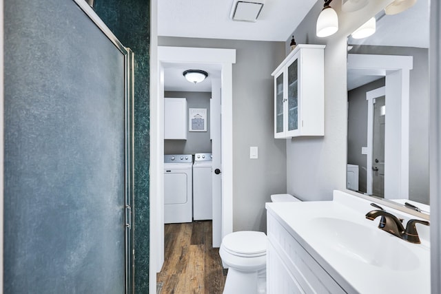 full bath with toilet, vanity, a shower stall, wood finished floors, and independent washer and dryer