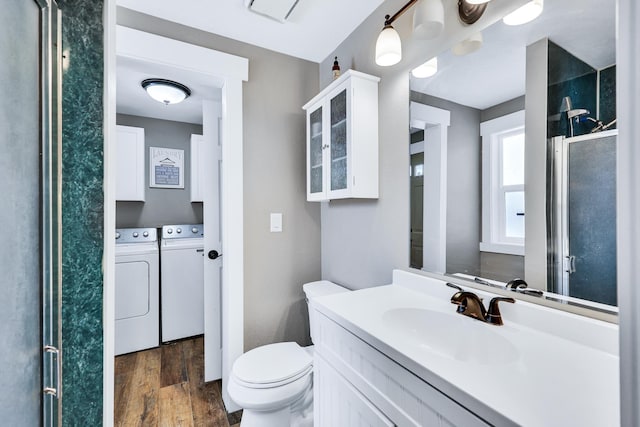 bathroom with toilet, wood finished floors, vanity, a shower stall, and separate washer and dryer