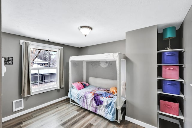 bedroom featuring a textured ceiling, baseboards, and wood finished floors