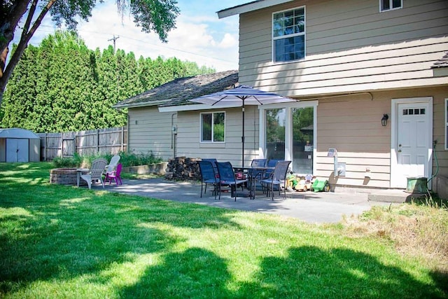 back of house with a storage unit, a lawn, a patio area, and an outdoor structure