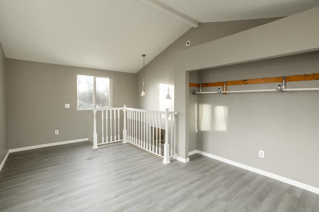 empty room with vaulted ceiling with beams, baseboards, and wood finished floors