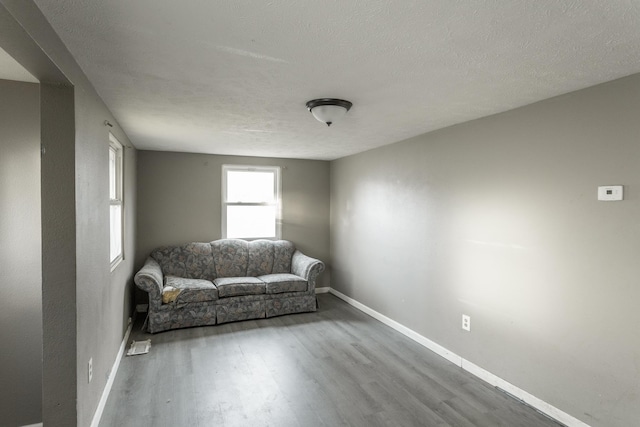 unfurnished room featuring a textured ceiling, baseboards, and wood finished floors