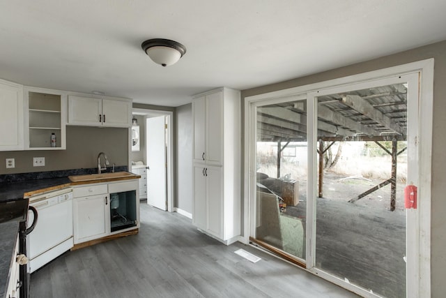 kitchen with dishwasher, dark countertops, a sink, and white cabinetry