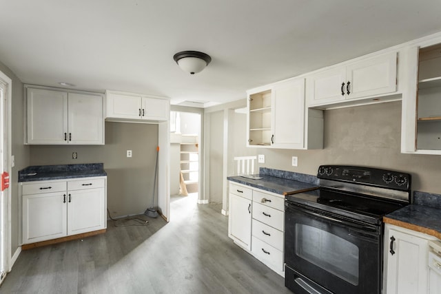 kitchen featuring dark countertops, white cabinets, and black range with electric stovetop