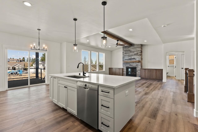 kitchen with a center island with sink, light countertops, open floor plan, a sink, and dishwasher