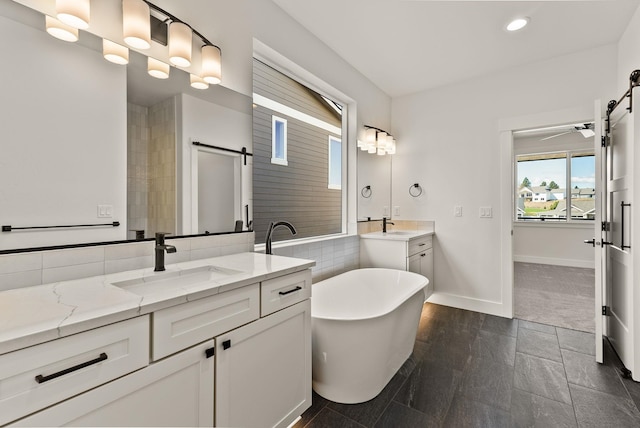 full bathroom featuring recessed lighting, a soaking tub, two vanities, a sink, and baseboards