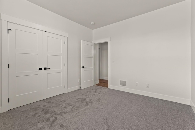 unfurnished bedroom featuring carpet floors, baseboards, visible vents, and a closet