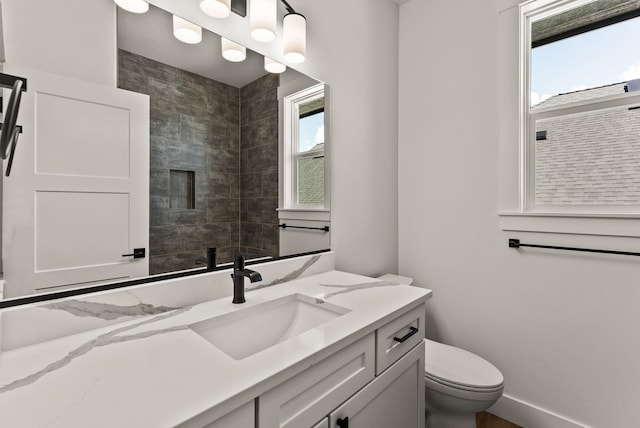 bathroom with toilet, plenty of natural light, vanity, and baseboards