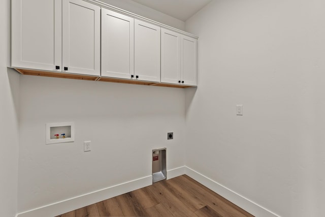 washroom featuring cabinet space, baseboards, wood finished floors, washer hookup, and electric dryer hookup