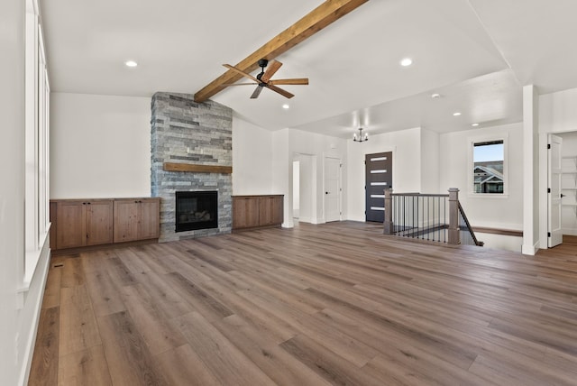 unfurnished living room featuring lofted ceiling with beams, a fireplace, wood finished floors, and recessed lighting