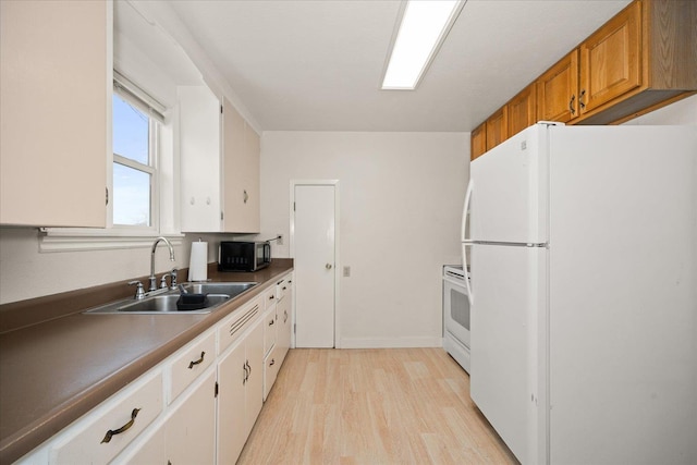 kitchen featuring dark countertops, brown cabinetry, light wood-style floors, a sink, and white appliances