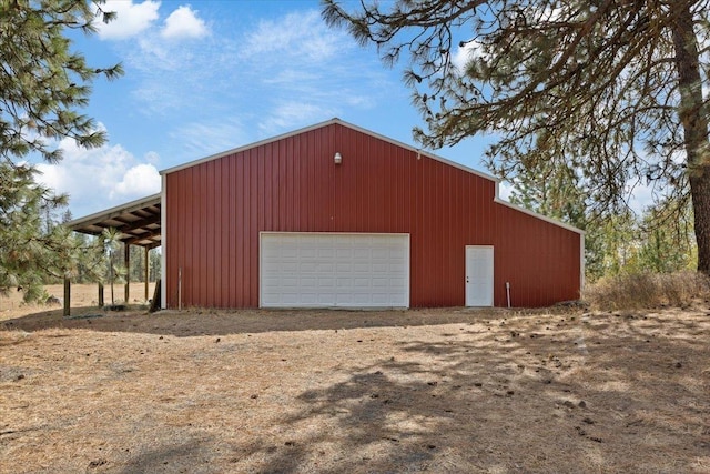 detached garage featuring dirt driveway and a carport