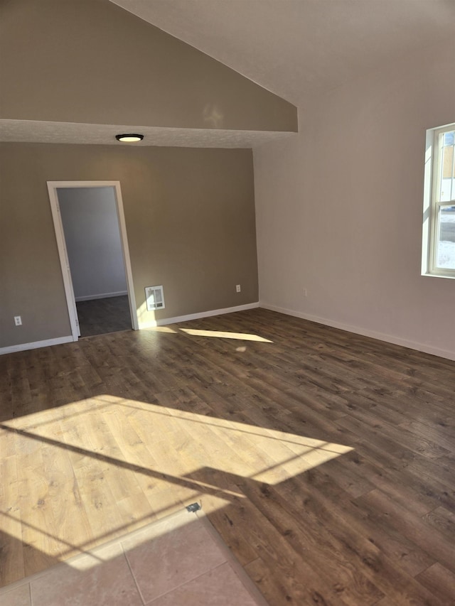 empty room with baseboards, vaulted ceiling, and dark wood-style flooring