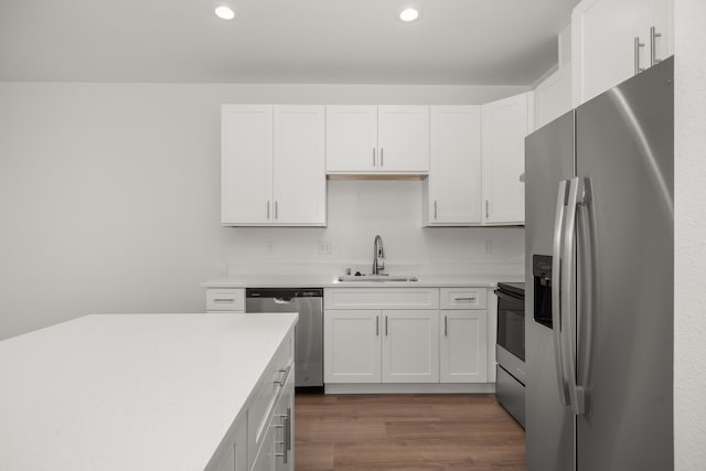 kitchen featuring dark wood-type flooring, a sink, white cabinets, light countertops, and appliances with stainless steel finishes