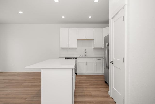 kitchen featuring light countertops, a center island, white cabinetry, and light wood finished floors