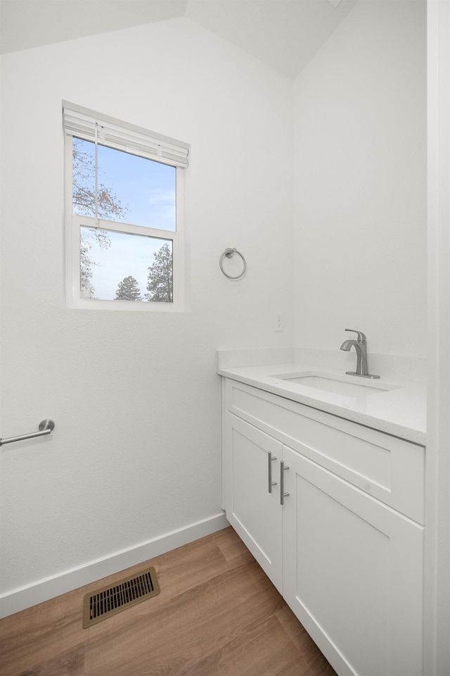 bathroom featuring baseboards, visible vents, lofted ceiling, wood finished floors, and vanity