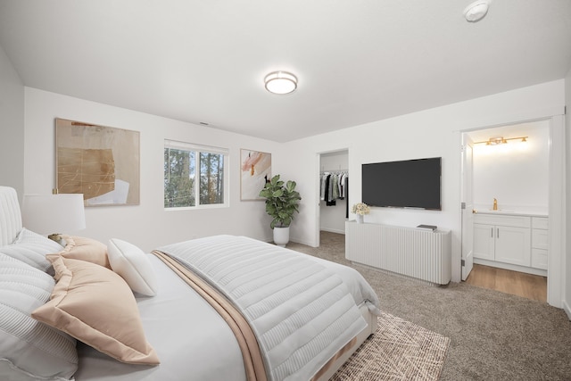 bedroom with a walk in closet, a closet, light carpet, and ensuite bathroom