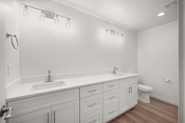 full bathroom featuring toilet, double vanity, a sink, and visible vents