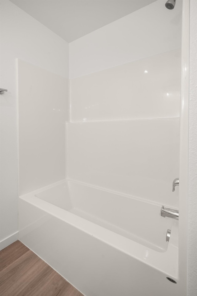 bathroom with washtub / shower combination and wood finished floors