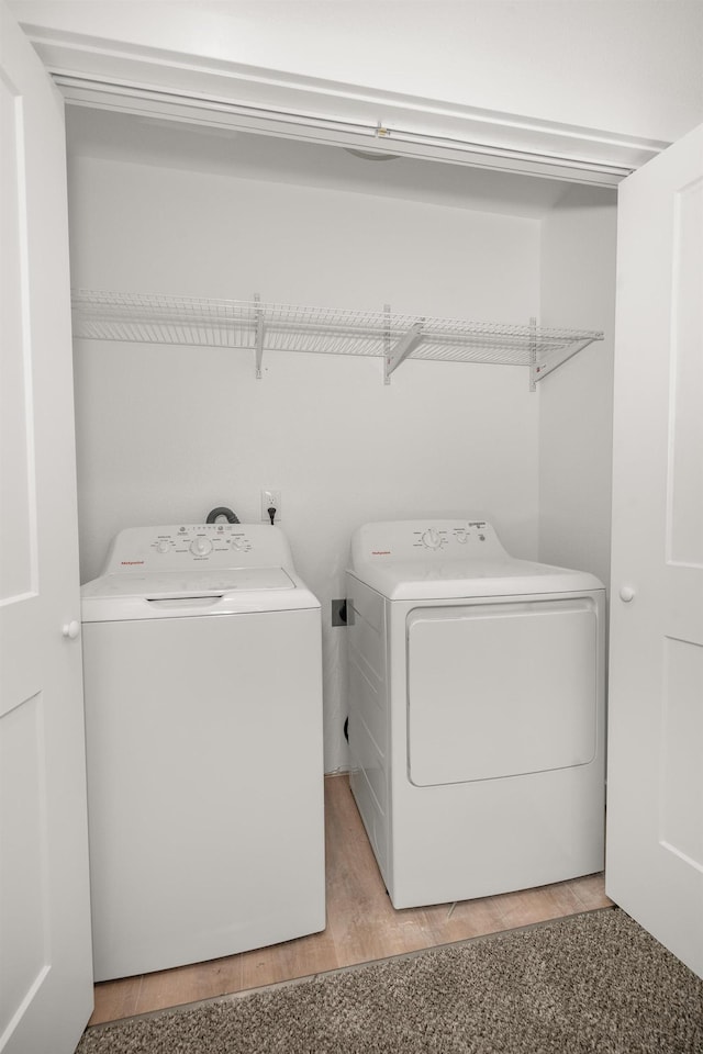 clothes washing area with light wood-type flooring, laundry area, and separate washer and dryer