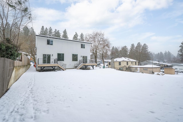 snow covered property featuring stairs, fence, and a deck