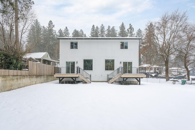 snow covered property with stairway and a deck