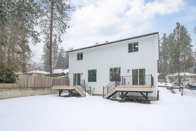 snow covered rear of property featuring a deck and stairs