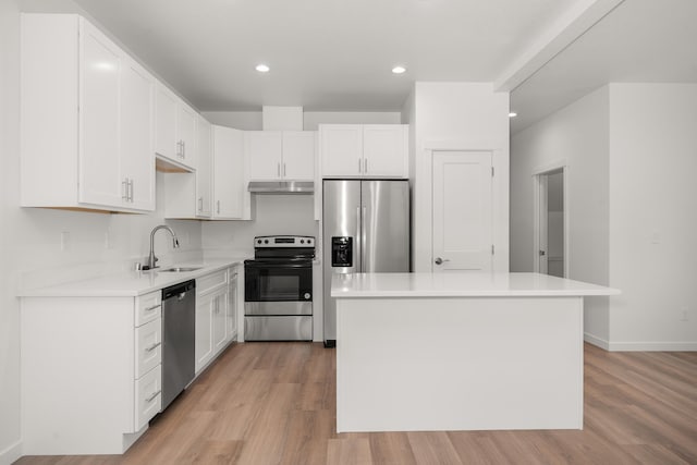 kitchen with appliances with stainless steel finishes, light countertops, a sink, and a center island